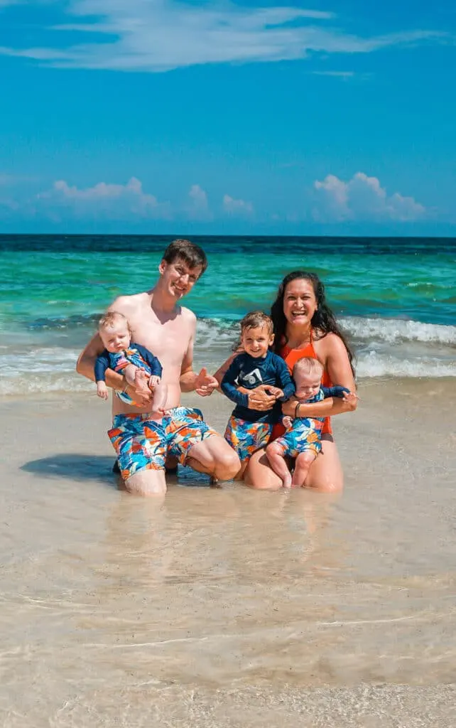 A family with three kids wearing matching swimsuits on the beach at La Zebra in Tulum.