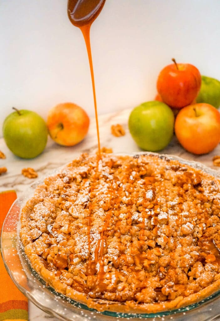 Caramel drizzling on top of an entire Caramel Apple Walnut Pie with a Streusel Topping.