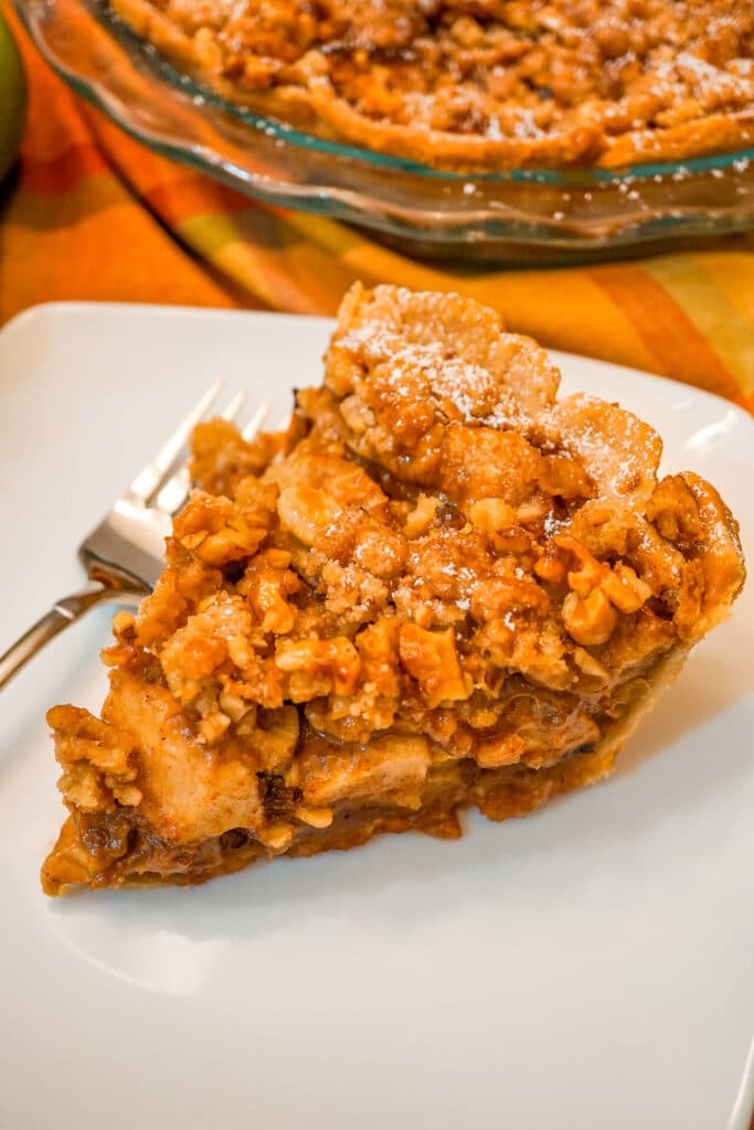 A slice of Caramel Apple Walnut Pie with a Streusel Topping on a white plate.