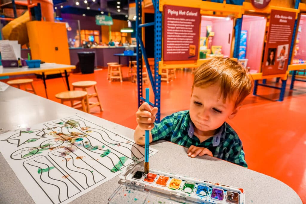 A toddler painting with watercolors at Crayola Experience in Plano - one of the best things to do in Dallas with toddlers.