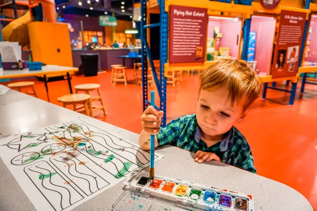 A toddler painting with watercolors at Crayola Experience in Plano - one of the best things to do in Dallas with toddlers.