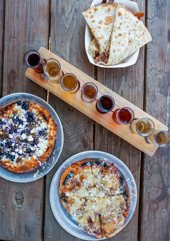 A blueberry and sausage flatbread, pear caramelized onion flatbread, pear quesadilla, and a flight of hard cider from The Gorge White House.