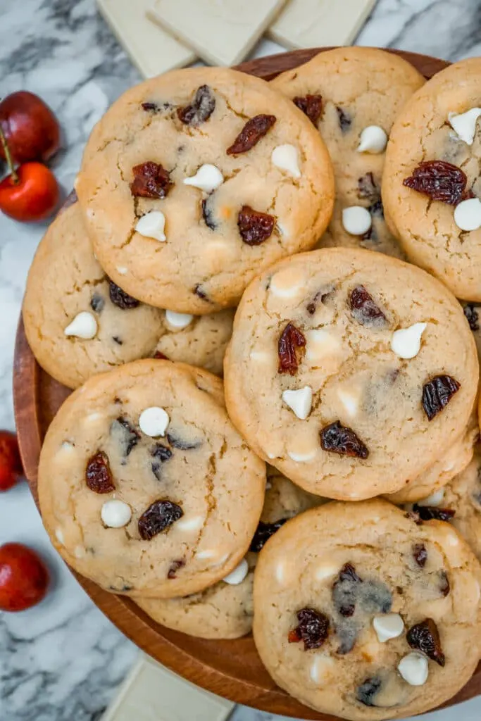 Several White Chocolate Cherry Cookies on a wooden platter.
