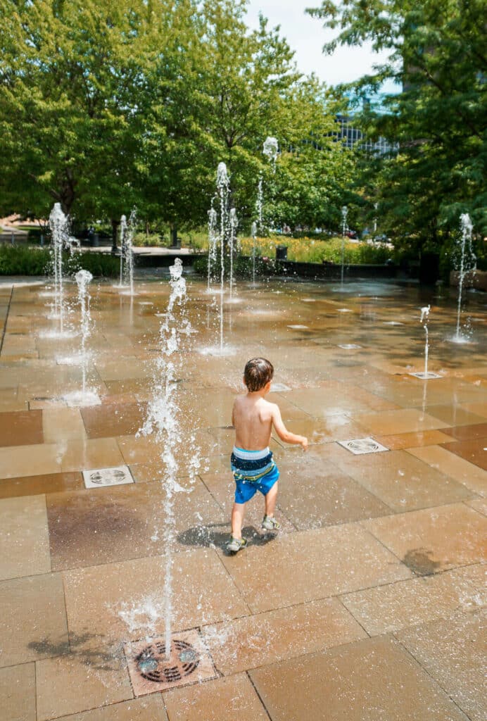 A boy running through water fountains on the spray plaza at the Citygarden in St. Louis.