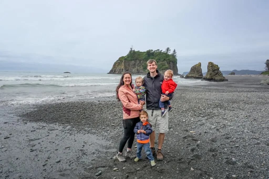 A family with three boys at Ruby Beach with sea stacks in the background.