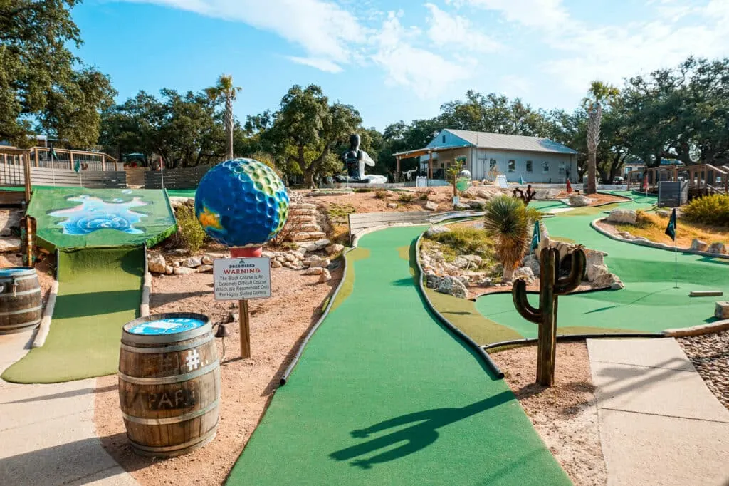 A challenging mini golf course with a giant golf ball painted like the globe at Dreamland - one of the best things to do in Dripping Springs. 