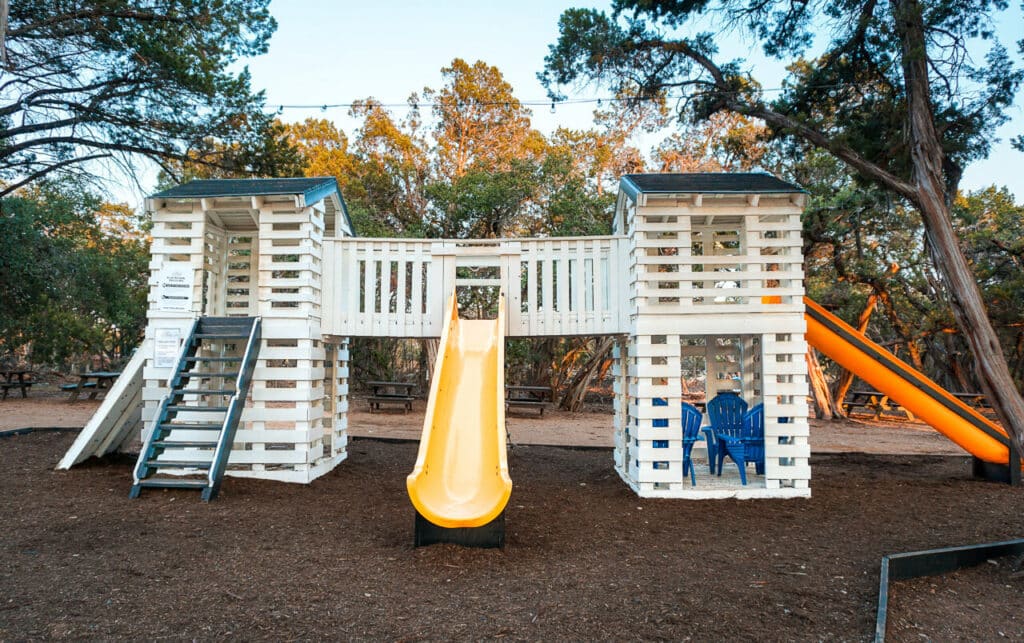A gorgeous white wooden playground with yellow slides located at Fitzhugh Brewery - one of the best kid-friendly breweries in Dripping Springs. 