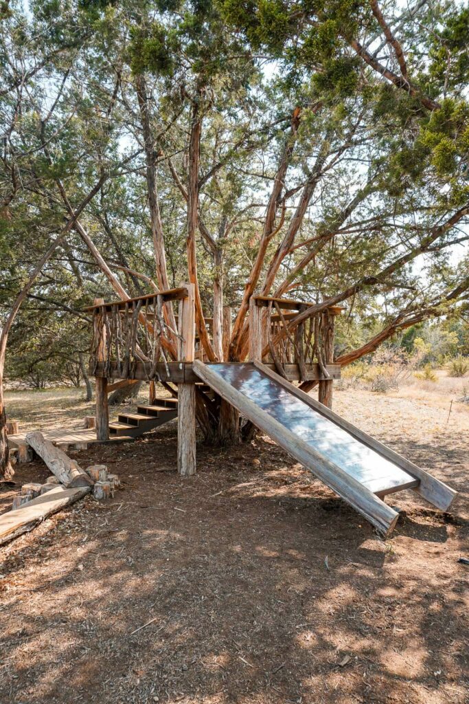 A wooden fort with a slide built around a tree. Located at Ghost Note Brewery in Dripping Springs.