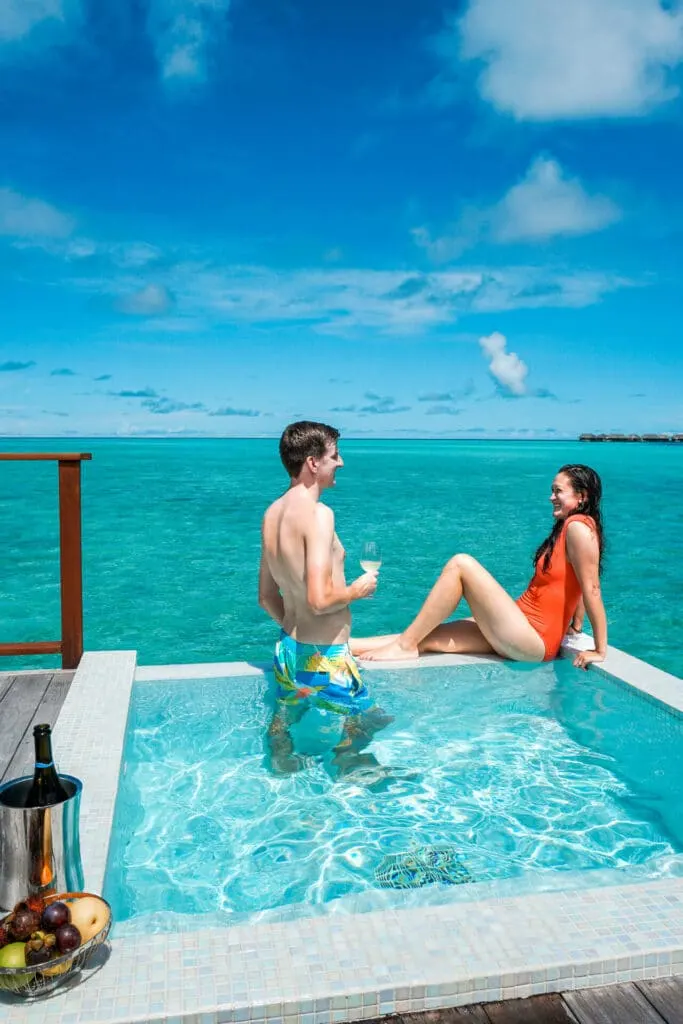 A couple relaxing in their plunge pool from the Sunrise Water Villa at Conrad Maldives Rangali Island.