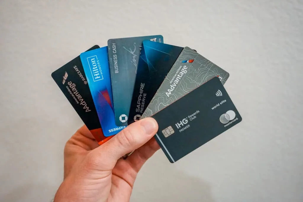 A hand holding several different travel credit cards.