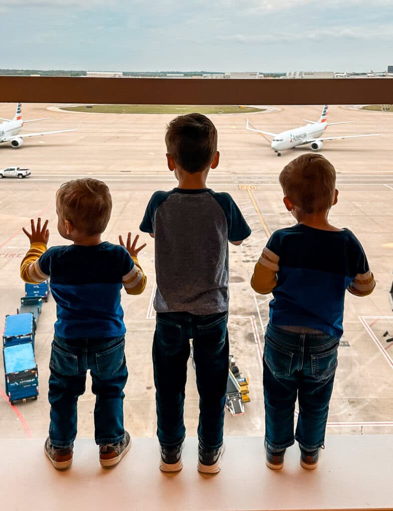 Three toddler boys watching planes at the DFW Capital One Lounge.