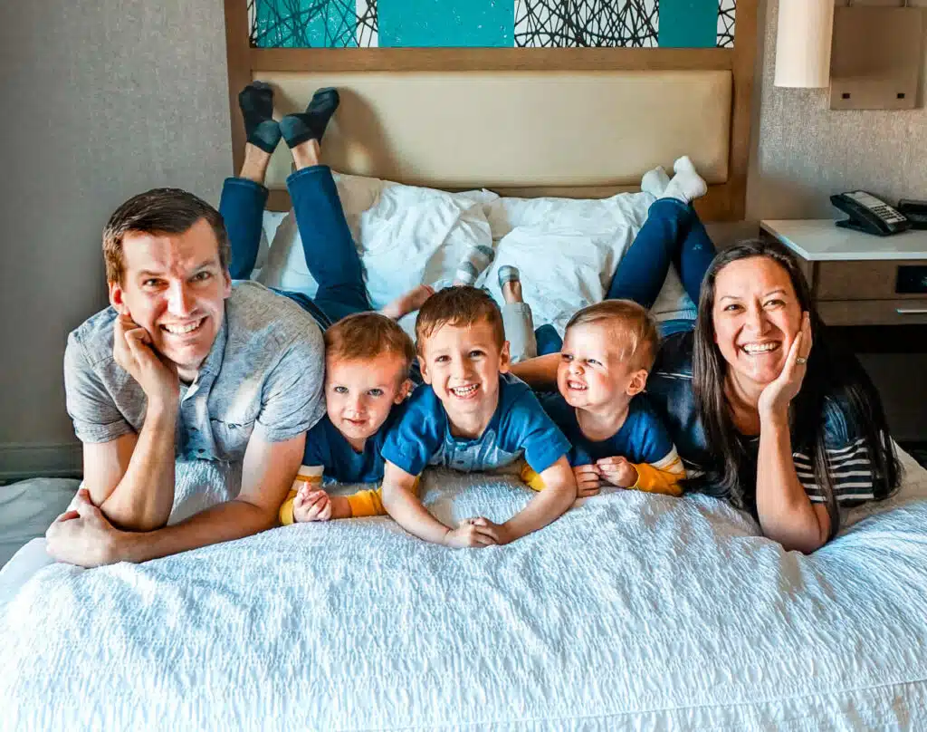 A family laying on a hotel bed.