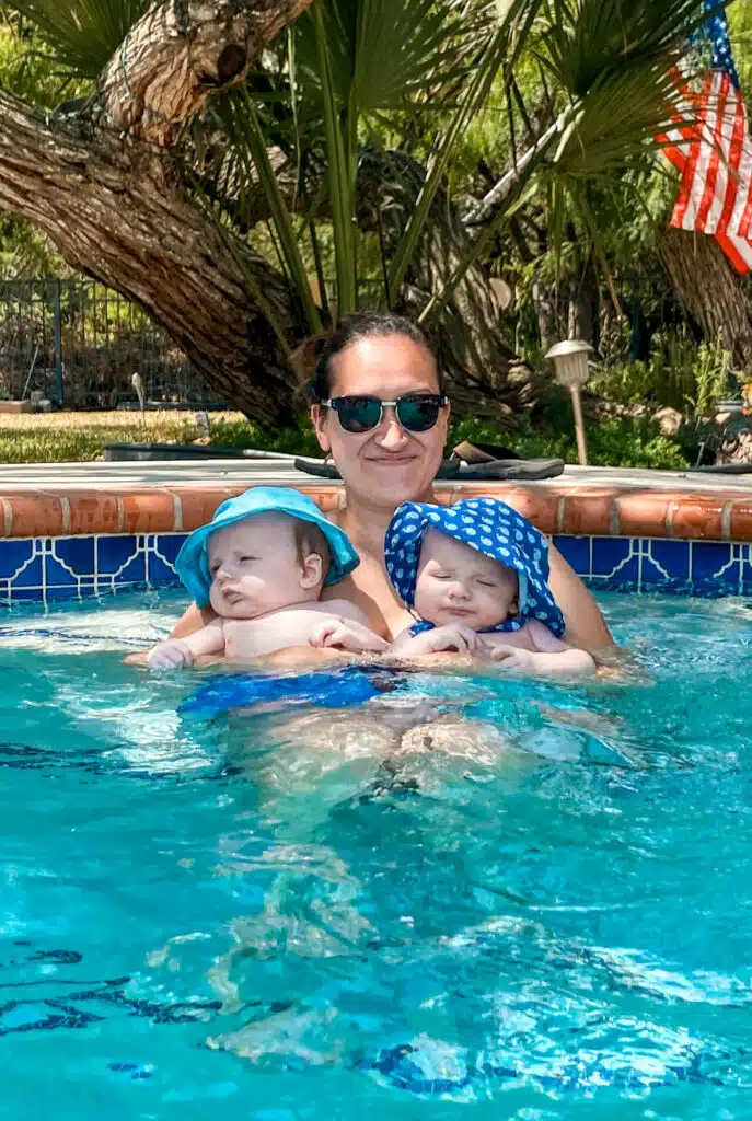 A mom holding her twin boys in the pool.