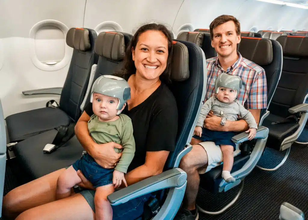A mom and dad flying with twins. Each parent holding a twin on the aisle seat. 
