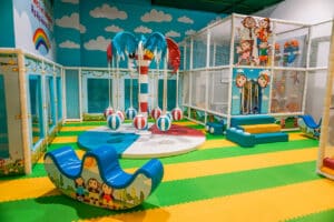 The colorful toddler play area at Cheeky Monkey—One of the best indoor playgrounds in Dallas. It has an enclosed ball pit, soft seesaw, merry-go-round, and more.