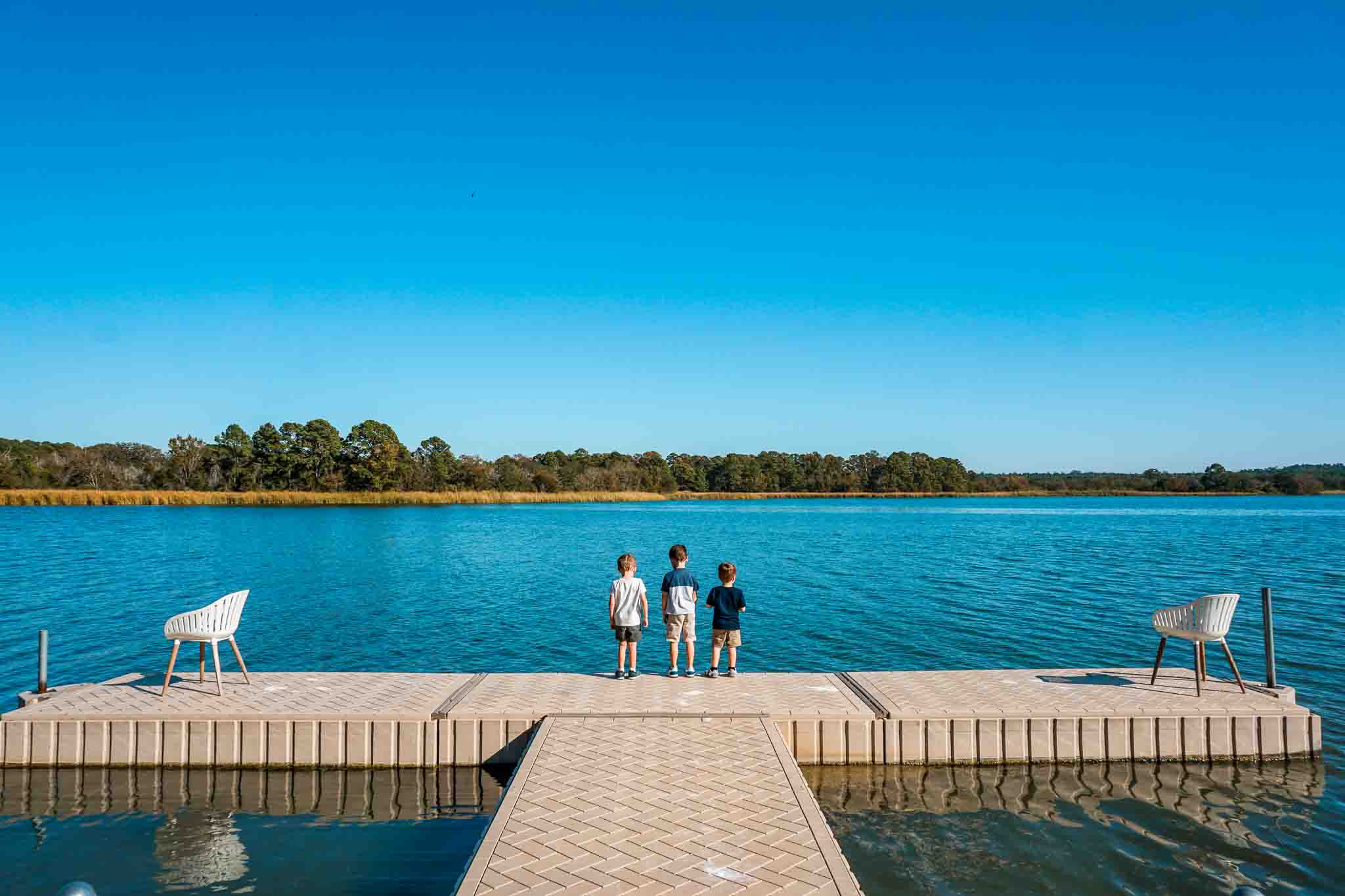 Three boys on a dock looking at fish at Lake Bastrop North Shore Park.
