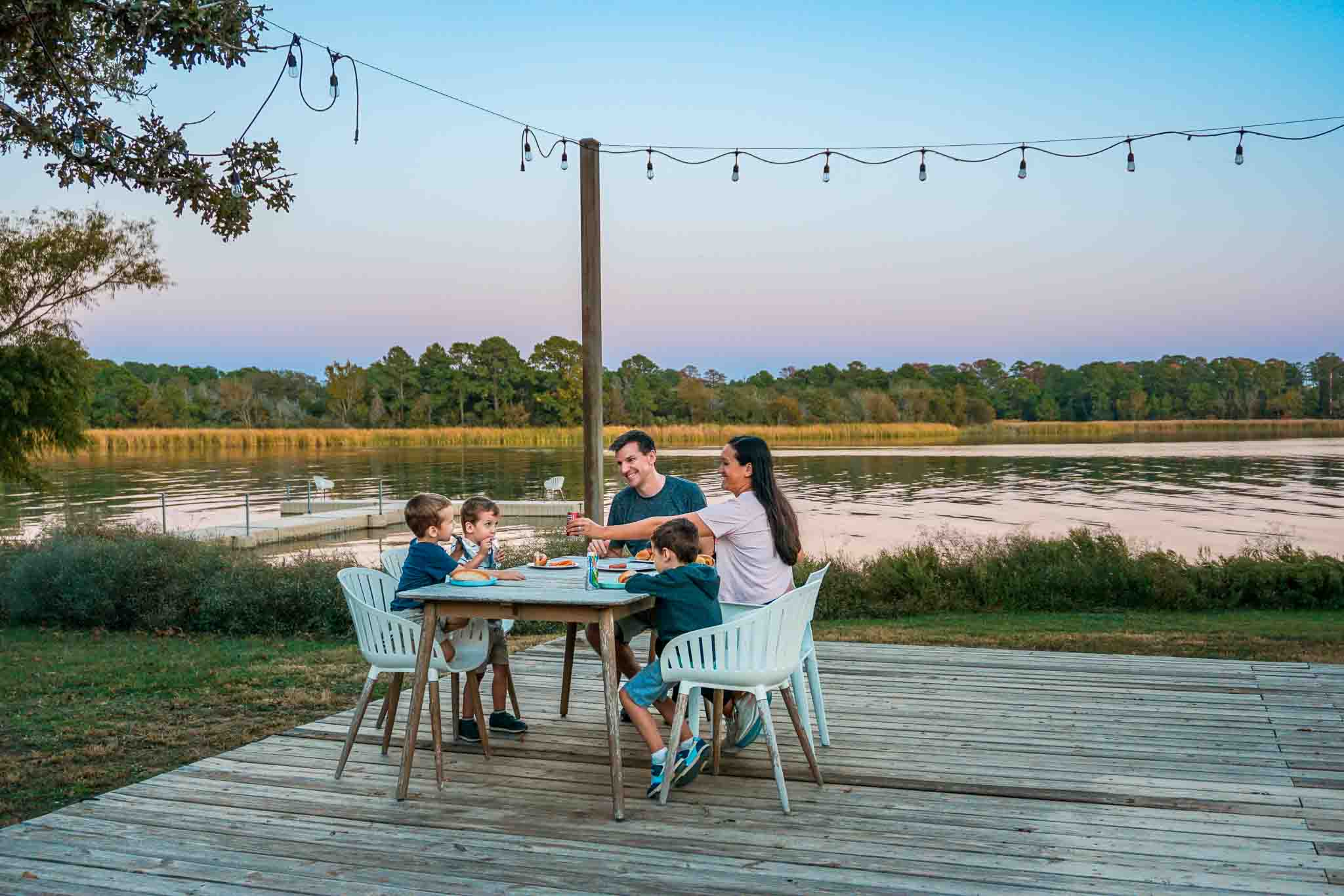 A family eating dinner on a patio next to Lake Bastrop during sunset at one of LCRA Parks, Lake Bastrop North Shore Park.