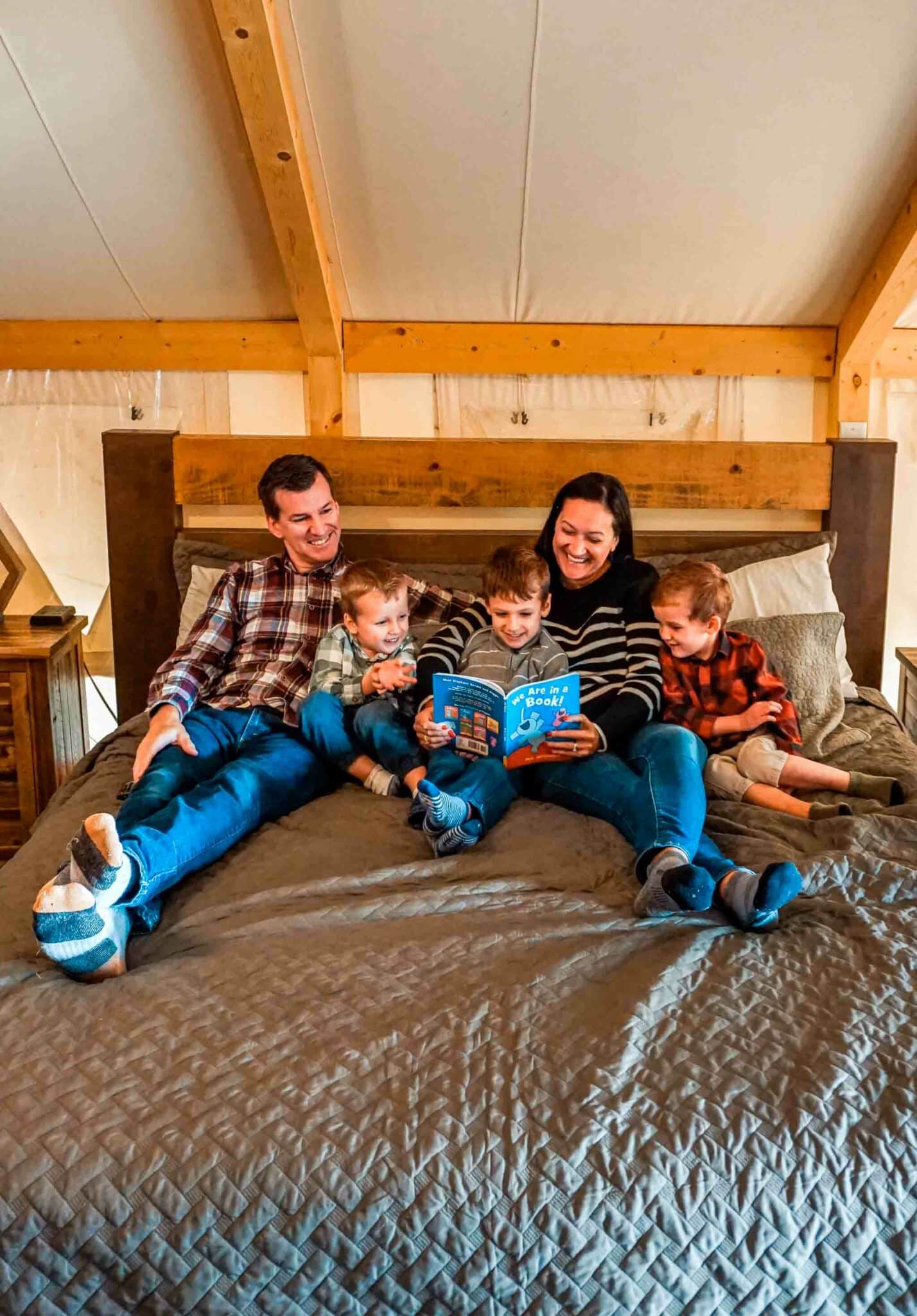 A family reading a book on their bed inside their safari tent at Lake Bastrop North Shore Park.