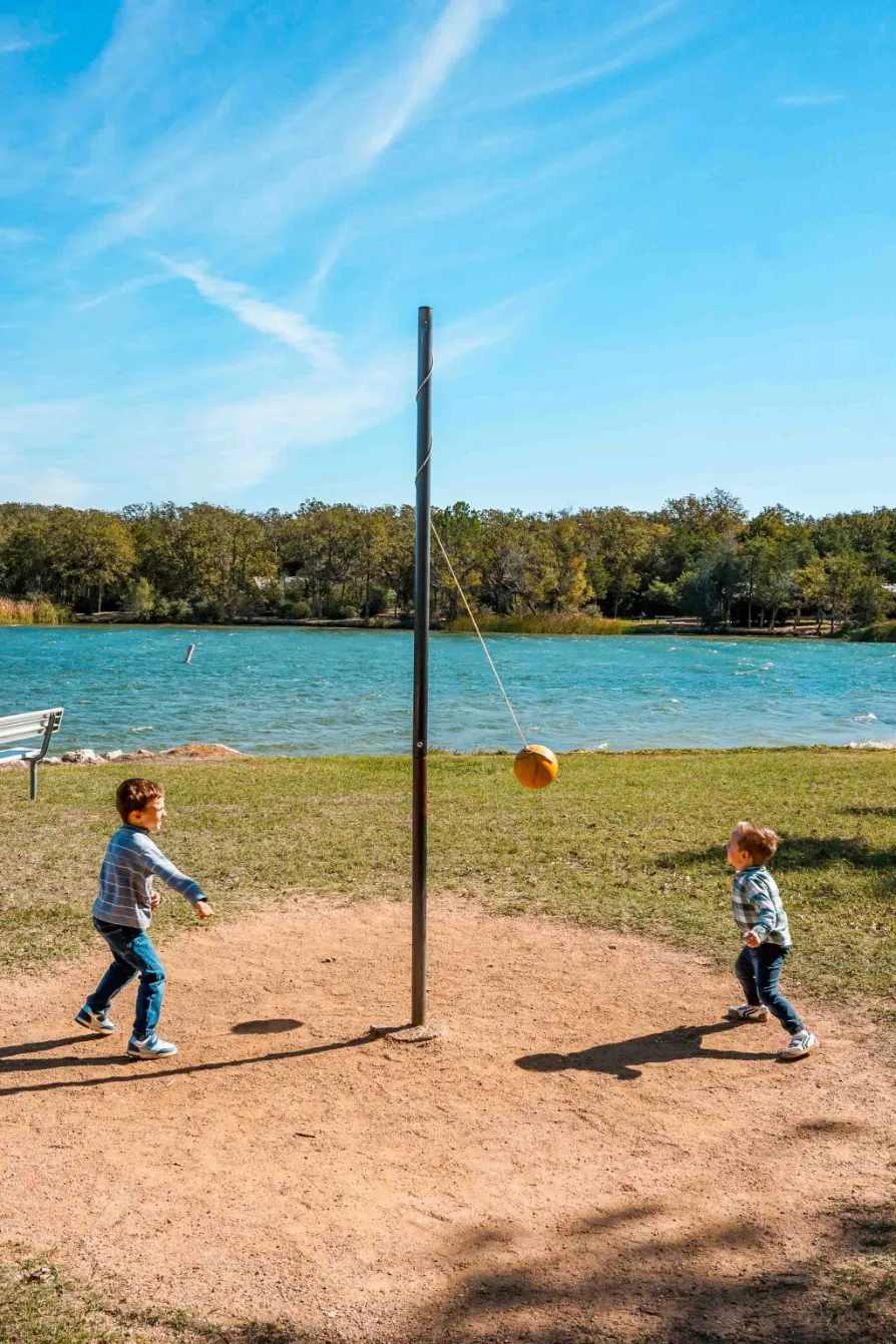 Two boys playing tetherball by the lake at Lake Bastrop South Shore Park.