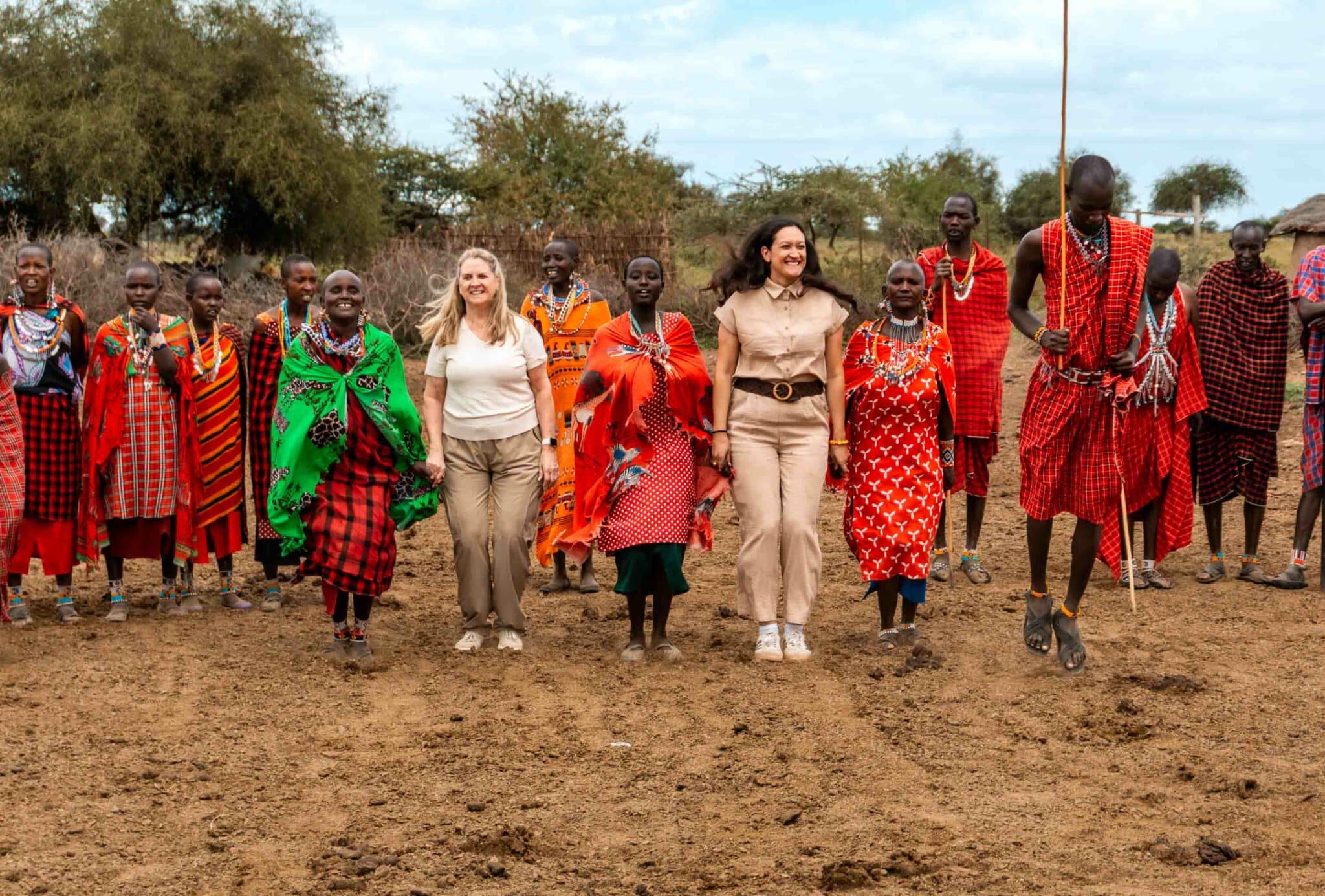 Two tourist women jumping with women from a Maasai tribe.