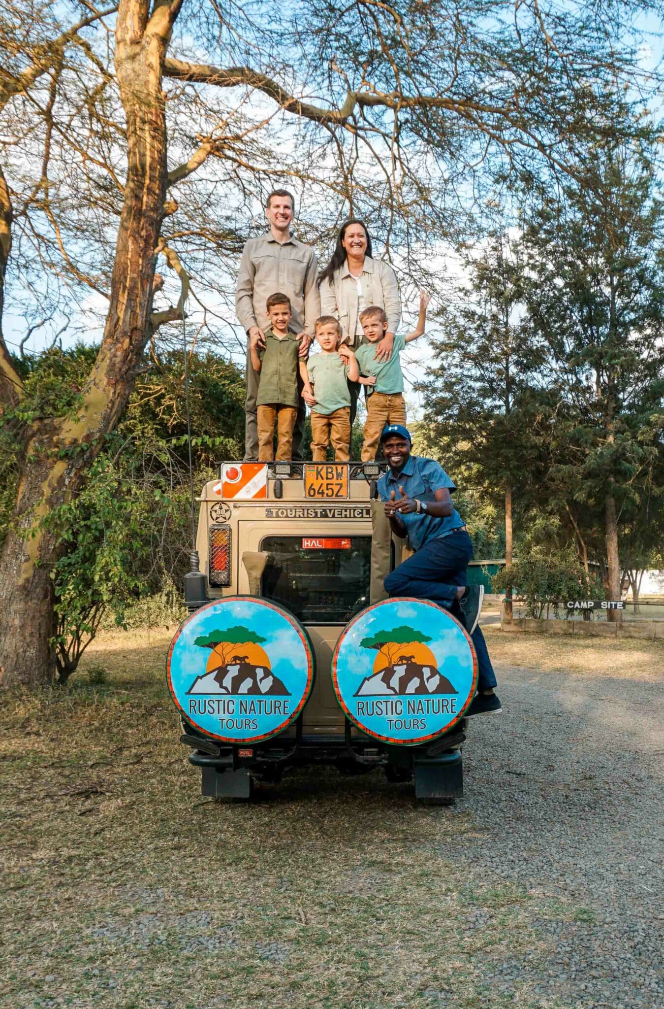 A family of five standing on top of a safari jeep from Rustic Nature Tours.