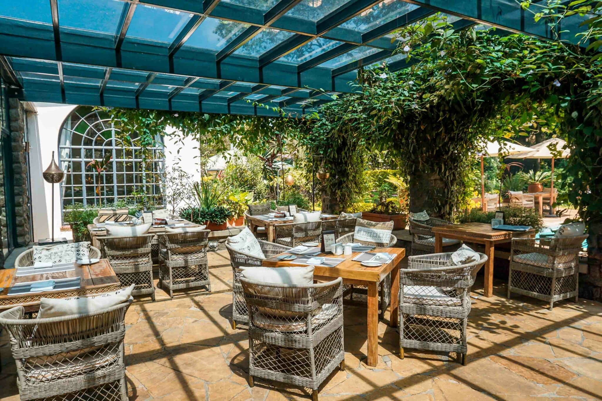 A gorgeous shaded outdoor dining area with a lush ivy green archways at Karen Blixen Coffee Garden House.